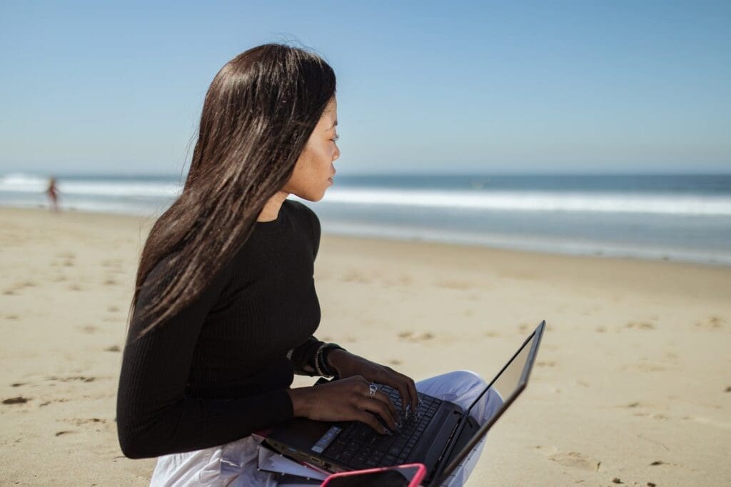woman in black long sleeve shirt using black laptop computer at the beach