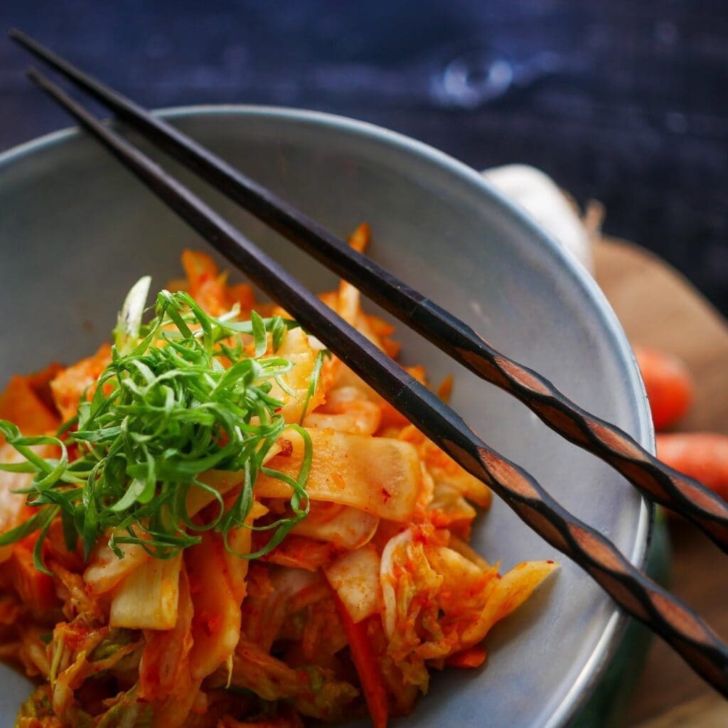 wooden chopsticks on top of a bowl with kimchi